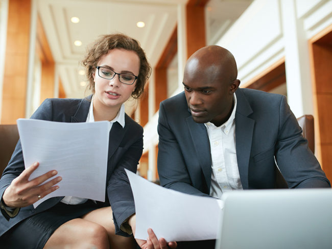 Two business partners sitting in cafe and discussing contract.
