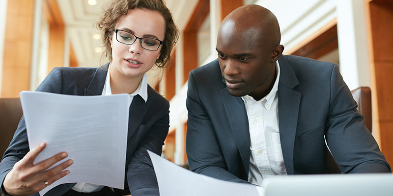 Two business partners sitting in cafe and discussing contract.